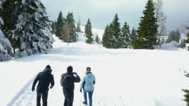 Üç kişi karda yürüyordu ve bir an için durdular ve dürbünle baktılar. Kış geldi..