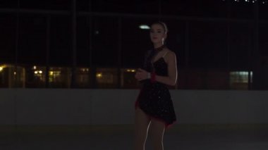 Genç bir artistik patinajcı koçuna bir şey sormak için buz pistinin kenarına doğru kayar..