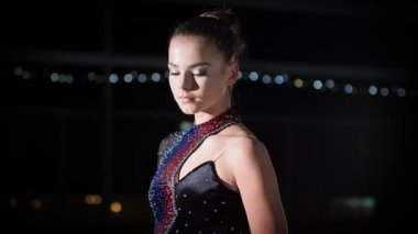 Genç bir buz patencisi kameranın önünde gülümsüyor ve poz veriyor. O zaman birini işaret ediyor..