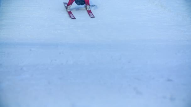 一个年轻的滑雪者几乎在他的滑雪板上坐了下来 然后他站起来 慢慢地停下来 — 图库视频影像