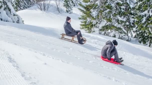 在一个晴朗的冬日里 两个人滑着雪橇下山 风景完全被雪覆盖了 — 图库视频影像