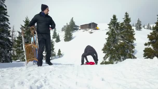 两个朋友在笑那个骑着一辆红色小雪橇滑下山的朋友 — 图库视频影像