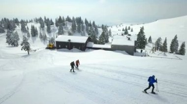 İnsanlar dağa tırmanıyor ve dağ kulübesinden uzaklaşıyorlar. Hava görüntüsü.