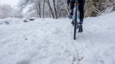 Bir adam karda bisikletini pedal çeviriyor ve dikkatli olması gerekiyor çünkü yollar kaygan..