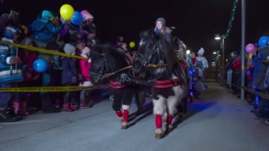 Noel Baba, Noel pazarına onu görmeye gelen çocukları selamlıyor. Atlı bir kızakla geliyor..