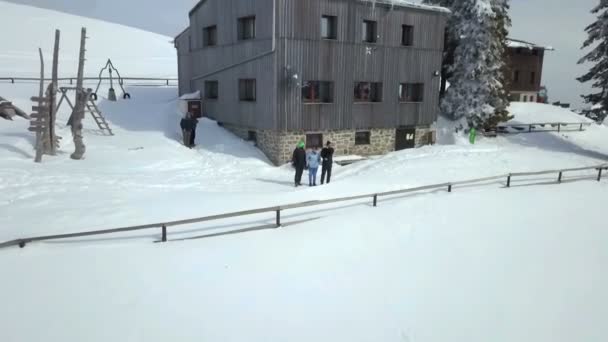 三个徒步旅行者站在山间小屋前面 雪覆盖了这个国家的风景 现在是冬天了 — 图库视频影像