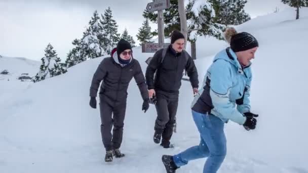若い女性が二人の男に雪玉を投げつける 彼らは皆笑顔で外にいて楽しい — ストック動画