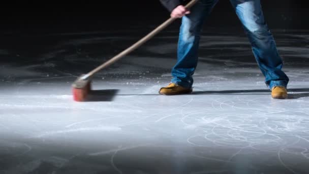 一个人正在用扫帚清扫冰块 以便一个年轻的表演者能在冰上滑冰 — 图库视频影像