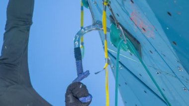 Bir adam spor salonunda tırmanma pratiği yapıyor. Çok dikkatli görünüyor..