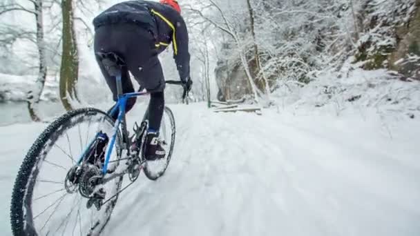 男が自転車を上り坂に乗ろうとしている 雪で道が滑りやすいので難しいです — ストック動画