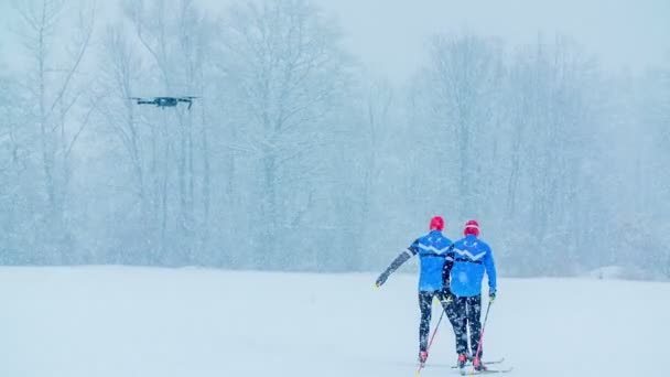 雪はたくさん降っていますが クロスカントリースキーであるこれらの2人の男を止めるものは何もありません 冬の時間だ — ストック動画