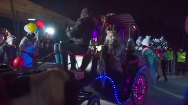 Noel Baba bir kızağın üstünde oturuyor ve onu gördüğüne gerçekten sevinen çocuklarla konuşuyor..