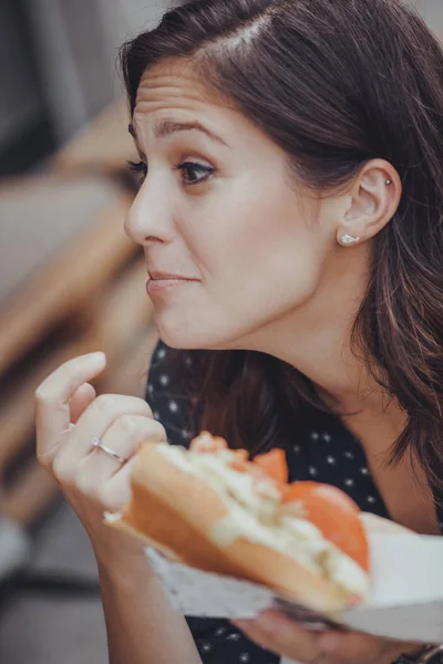 Mladá žena jíst párek v rohlíku — Stock fotografie
