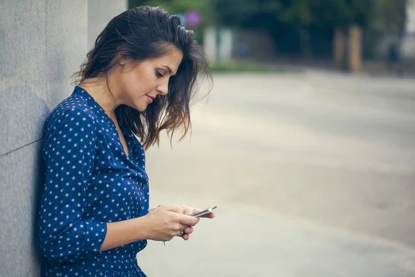 Mujer joven apoyada contra el edificio — Foto de Stock