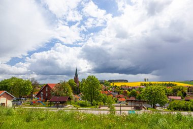 Gietrzwald - Polonya 'nın Warmia ve Mazury bölgesinde bir köy - bahar manzarası, çiçek açan kolza tohumu. Kutsanmış Bakire Meryem 'in Doğumu Bazilikası Gietrzwald' da.
