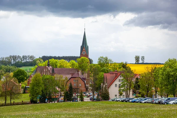 Gietrzwad - Polonya 'nın Warmia ve Mazury kentlerinde bir köy - bahar manzarası, çiçek açan kolza tohumu. Gietrzwad 'daki Kutsal Bakire Meryem' in Doğumu Bazilikası.