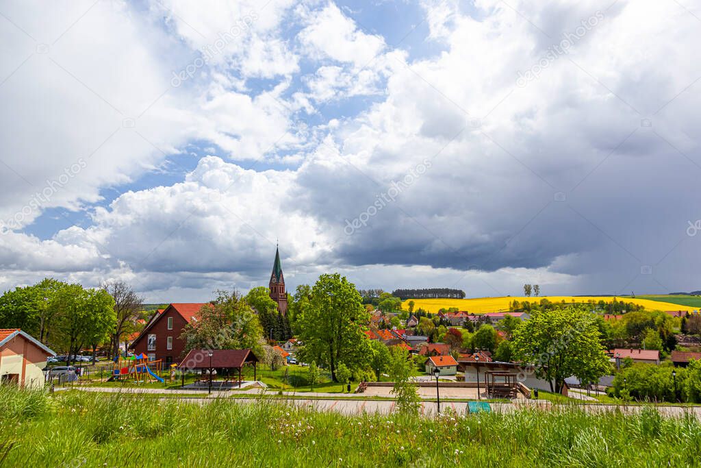 Gietrzwald - a village in Warmia and Mazury, Poland - spring landscape, blooming rapeseed. Basilica of the Nativity of the Blessed Virgin Mary in Gietrzwald.