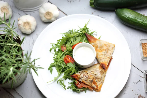 Vegetarisch eten. Knoedels van filodeeg gevuld met groenten en champignons, geserveerd met knoflooksaus en groene salade — Stockfoto