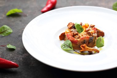 Beyaz bir tabakta servis edilen sebze ve yumurta ile pişirilmiş Chanterelle mantarları..