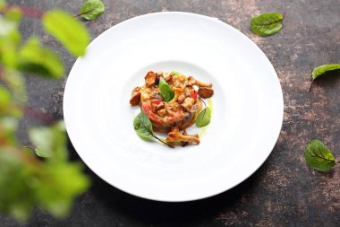 Beyaz bir tabakta servis edilen sebze ve yumurta ile pişirilmiş Chanterelle mantarları..