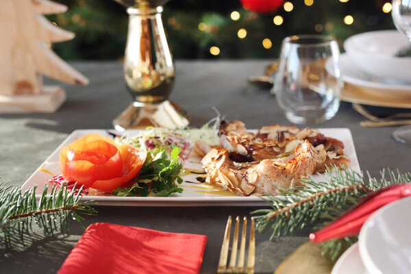 Fish baked in almonds, an elegant dish on a festive table. Traditional Christmas dishes, festive table setting. Horizontal composition.
