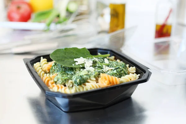 Catering, food out of the box. Appetizing pasta with spinach and cream cheese sauce.