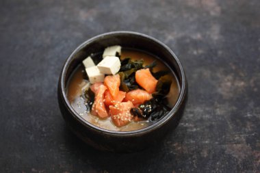 Tofulu ve yosunlu Ramen somonu, geleneksel Japon çorbası. Koyu bir arka planda yemek.