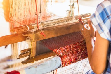 Sarı iplikli çark ipliği dokuma makinesi ve Tayland geleneksel ipeği için çalışıyor. Sanatçılar el sanatları el yapımı motton ipek el işi tezgahlar.. 