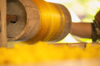 Sarı iplikli çark ipliği dokuma makinesi ve Tayland geleneksel ipeği için çalışıyor. Sanatçılar el sanatları el yapımı motton ipek el işi tezgahlar.. 