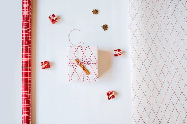 Christmas gift paper and a wrapped gift on white background. Flatlay. — Stock Photo, Image