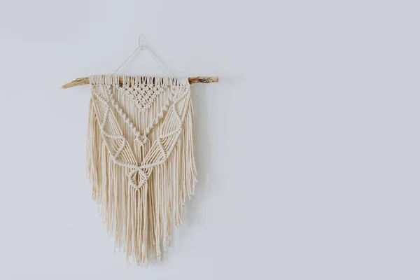 Handmade macrame decoration hanging on a white empty wall. Stock Picture