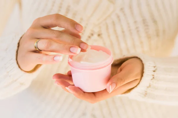 Close up with woman hands holding cosmetic product or cream.