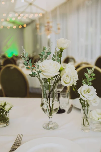 Festive dinner table, decorated with bunch of white roses.