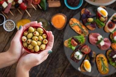 Lokantada ellerini masaya koyan ve insanlara bir sürü tapas ikram eden bir adam.