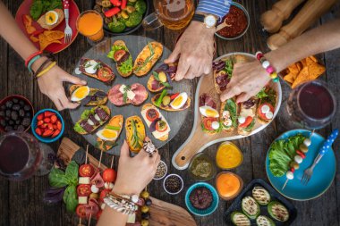Lokantada ellerini masaya koyan ve insanlara bir sürü tapas ikram eden bir adam.