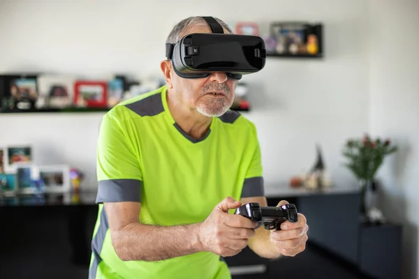 An elderly man plays video football game with virtual reality goggles and joystick , Hi-tech concept with vr glasses