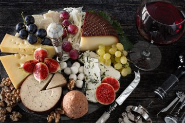 Kırmızı şarap şişede ve bardakta aperatif, şarap konsepti peynir tahtası, incir ve üzüm.. 