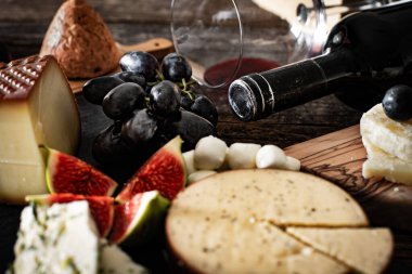 Kırmızı şarap şişede ve bardakta aperatif, şarap konsepti peynir tahtası, incir ve üzüm.. 