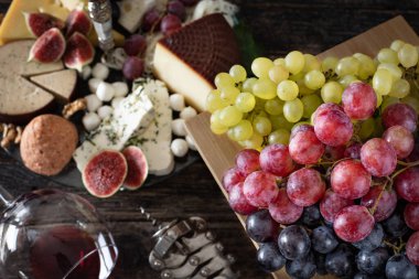 Kırmızı şarap şişede ve bardakta aperatif, şarap konsepti peynir tahtası, incir ve üzüm.. 