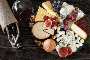 Kırmızı şarap şişede ve bardakta aperatif, şarap konsepti peynir tahtası, incir ve üzüm.. 