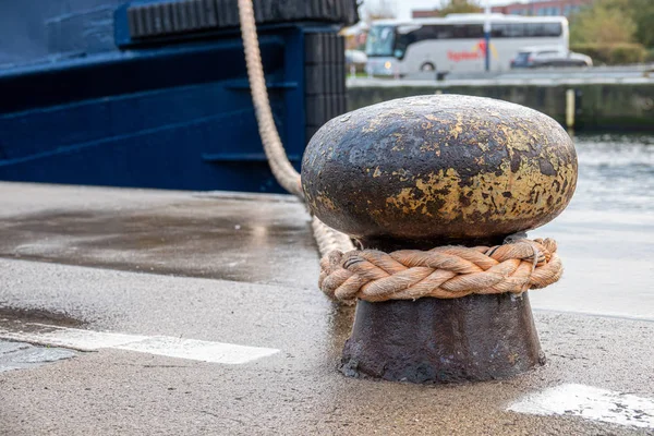 Ein Schiff wird mit einem dicken Seil an einem Poller im Hafen befestigt — Stockfoto