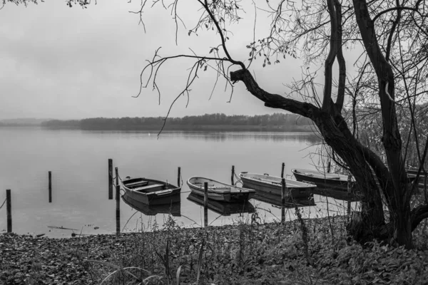 En un lago hay varios botes de remos en la orilla y que un — Foto de Stock