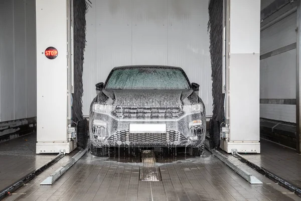 Un coche negro se coloca en un lavado de coches y se lava — Foto de Stock