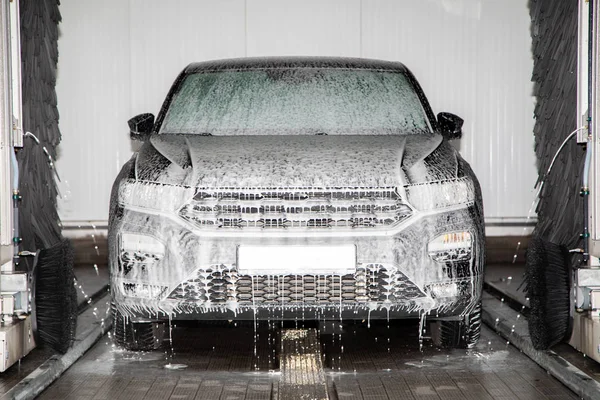 Un coche negro se coloca en un lavado de coches y se lava — Foto de Stock