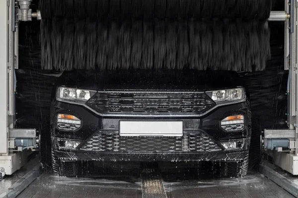 Un coche negro se coloca en un lavado de coches y se lava — Foto de Stock