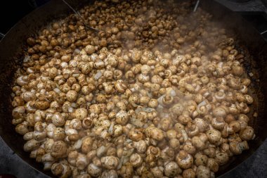 Dev bir tavada, lezzetli sarımsaklı mantarlar hazırlanır.