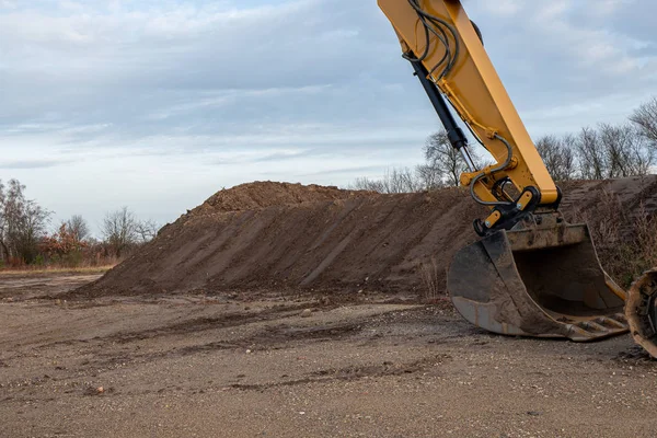 Kopacz z dużą łopatą usuwa górę ziemi — Zdjęcie stockowe