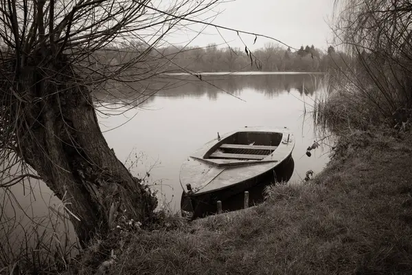 Opuštěný veslařský člun kotví na břehu jezera a — Stock fotografie