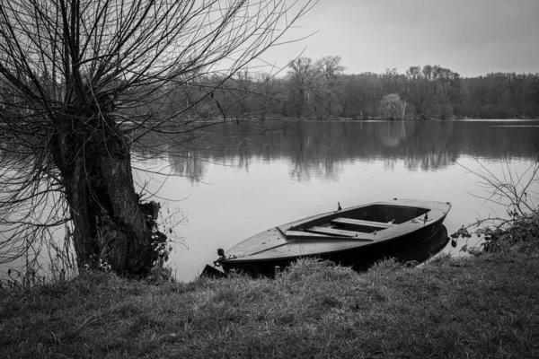 Un bote de remos abandonado se encuentra amarrado en la orilla de un lago y — Foto de Stock