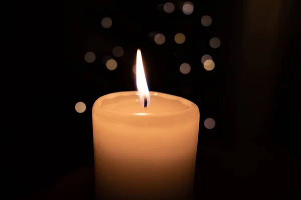 White burning candle stands before a dark background — Stockfoto